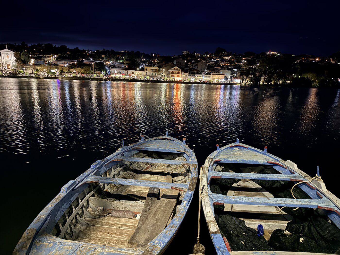 Boats and town lights reflected in calm water